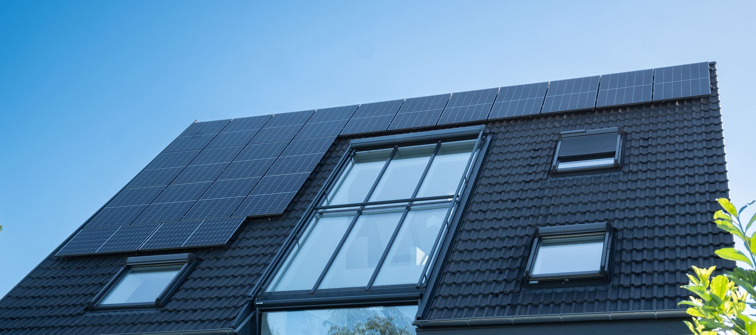 Photovoltaikanlage auf dem Schrägdach eines Einfamilienhauses mit großflächigen Solarmodulen und Dachfenstern