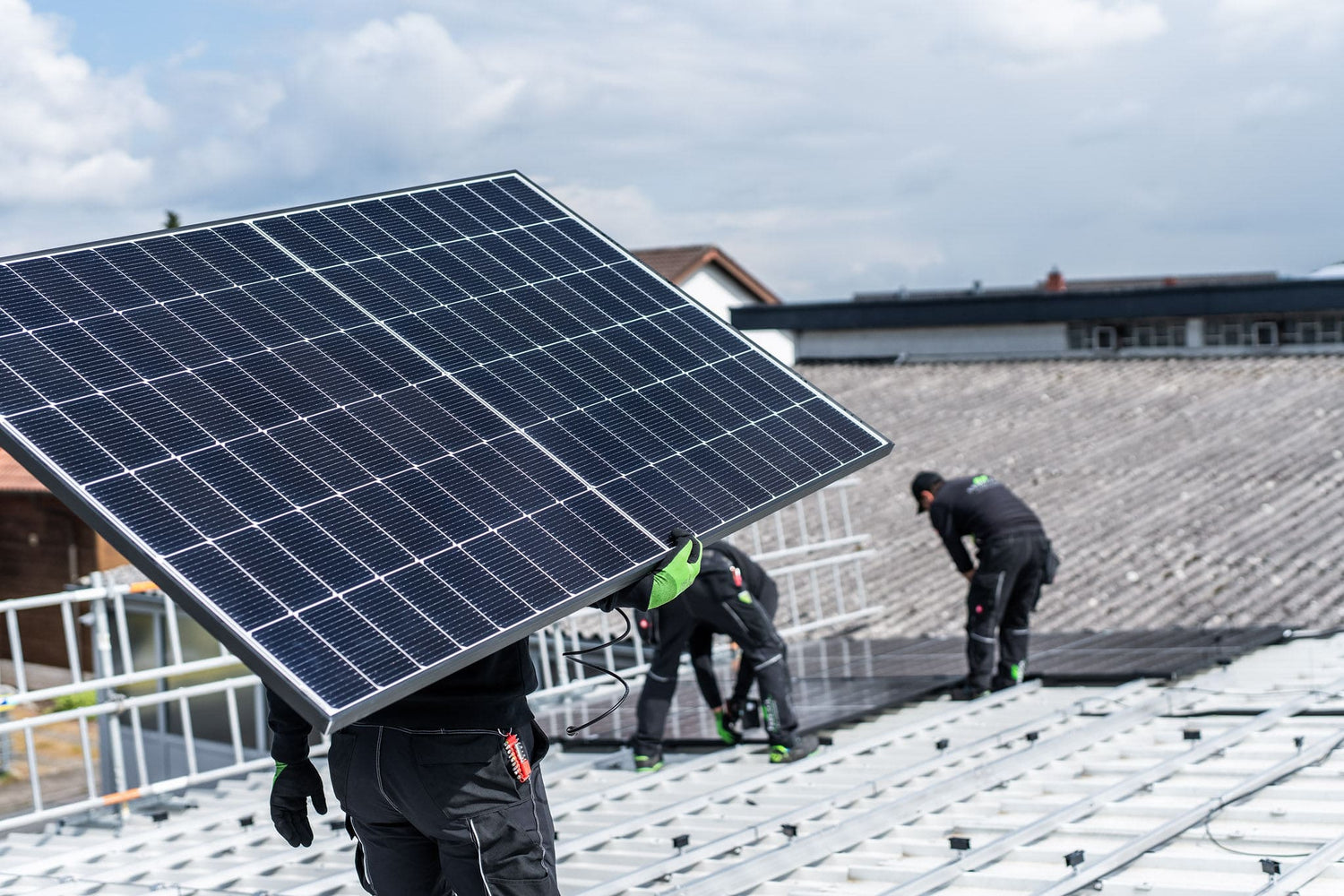 Installateure montieren Solarmodule auf einem Hausdach während der Installation einer Photovoltaikanlage